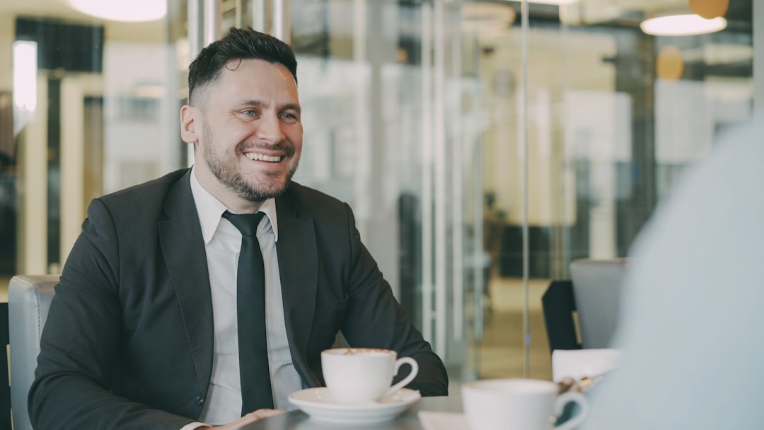 Man in suit smiling at cafe table with coffee